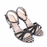 Black strappy high-heeled sandals with a multicolor patterned sole and crisscross front straps.