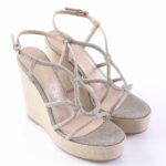 Glittery silver wedge sandals with multiple straps and open toes on a beige platform.