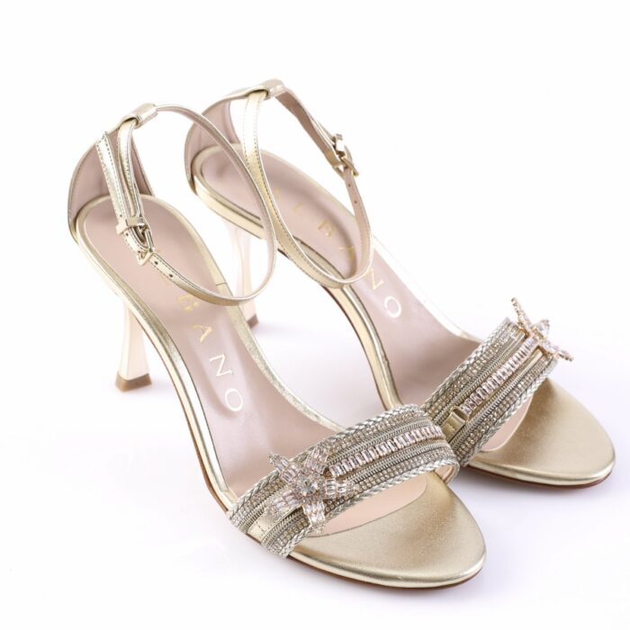 Gold high-heeled sandals with ankle straps and a rhinestone-encrusted front band, shown from a side angle; elegant party footwear.