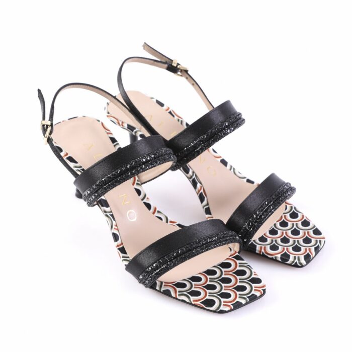 Open-toe black sandals with glittery straps and a patterned multicolor insole, shown from a side angle on a white background