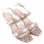 Pale pink strappy heeled sandals with crystal-embellished bands and a colorful patterned sole; open-toe design and ankle strap.