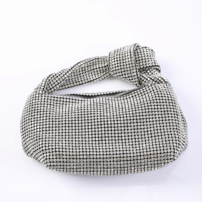 Silver rhinestone clutch bag with a twisted strap and rounded shape.