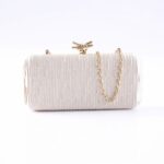 White textured clutch purse with a gold chain strap and knotted clasp on top