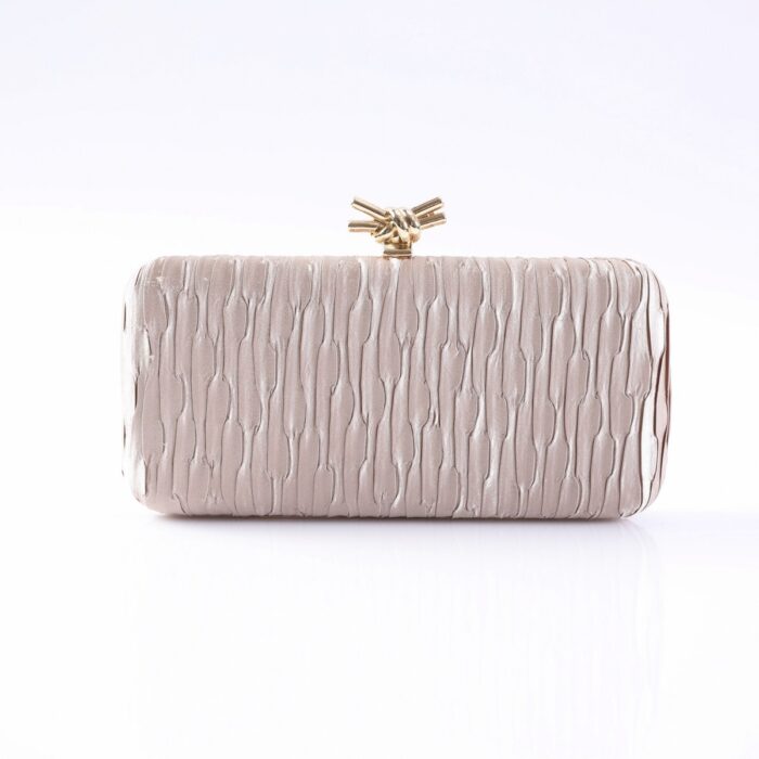 Beige quilted clutch purse with a gold knot clasp, resting on a white surface.