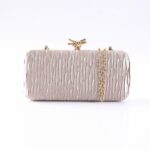 Pink satin clutch with vertical pleats, gold-tone chain strap, and knotted clasp on top.