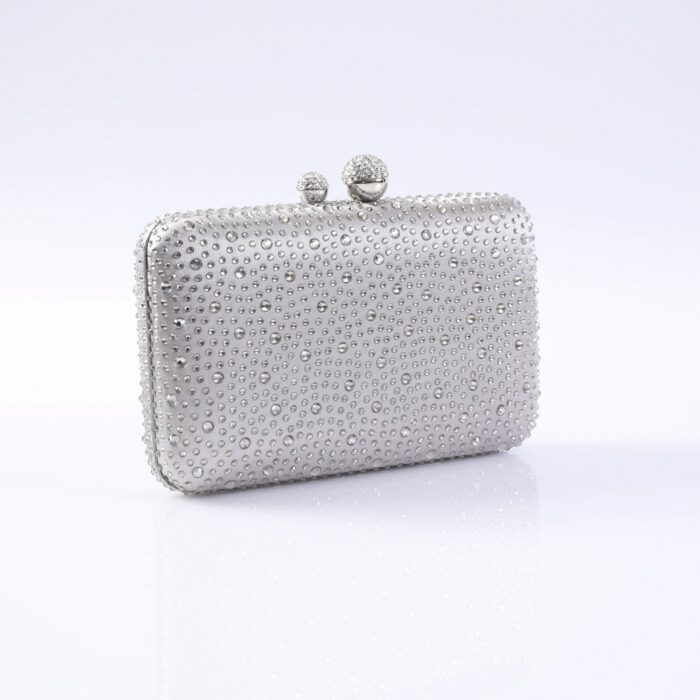 Silver rhinestone-encrusted clutch purse with a beaded ball clasp on a reflective surface