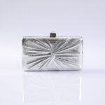 Silver metallic clutch purse with a radial, pleated pattern on a white reflective surface.