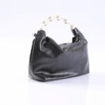 Small black leather handbag with a white pearl bead handle on a white surface.