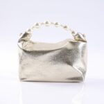 Gold metallic clutch purse with a pearl bead handle resting on a white surface.