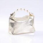 Gold metallic clutch purse with a pearl bead handle on a white surface.