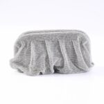 Silver beaded clutch bag on a white surface, reflecting light from many tiny studs.