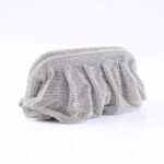 Shimmering silver bead-embellished clutch bag resting on a white surface in a studio setting.