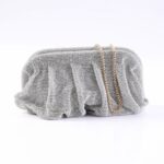 Silver beaded clutch purse with a gold chain strap resting on a white surface.