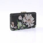 Black beaded clutch purse featuring a white-pink flower and green leaves, with a small gold clasp on top.