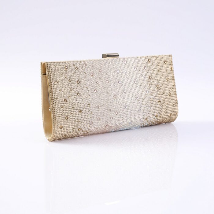 Gold clutch purse covered in rhinestones with a metal clasp on top, resting on a reflective white surface.