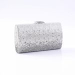 Silver clutch purse encrusted with rhinestones on a white surface, with a small clasp on top.