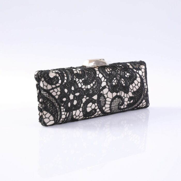 Black lace evening clutch with a metallic clasp, resting on a reflective white surface and subtle shadowing.