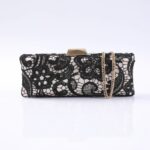 Black lace clutch purse with a gold chain strap and a metallic clasp on a white background