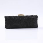 Black lace clutch purse with a gold metal clasp on a white surface, viewed from the front.