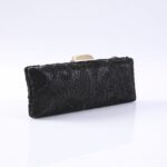 Black lace-clad evening clutch with a metallic clasp, resting on a white reflective surface