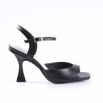 Black leather open-toe sandal with a thin ankle strap and silver buckle, displayed on a white studio background