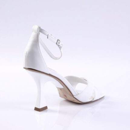 White open-toe sandal with ankle strap and curved high heel on a white backdrop﻿.