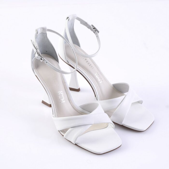 White open-toe high-heeled sandals with crisscross front straps and an ankle buckle on a white background.