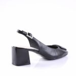 Black slingback pump with a chunky block heel and a silver buckle strap on a white reflective backdrop