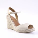 Cream espadrille wedge sandal with peep-toe and ankle strap featuring a gold buckle.
