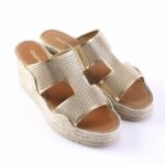 Gold metallic wedge sandals with perforated straps and a woven espadrille-style sole on a white background, viewed from a three-quarter angle.