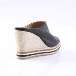 Black leather espadrille wedge with natural braided jute sole and black stripe trim, shown from rear-left.