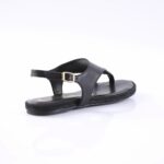 Black flat sandal with an adjustable ankle strap and gold buckle on a white studio background