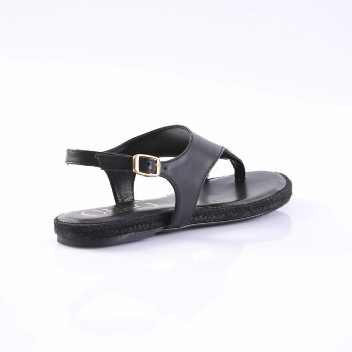 Black flat sandal with an adjustable ankle strap and gold buckle on a white studio background
