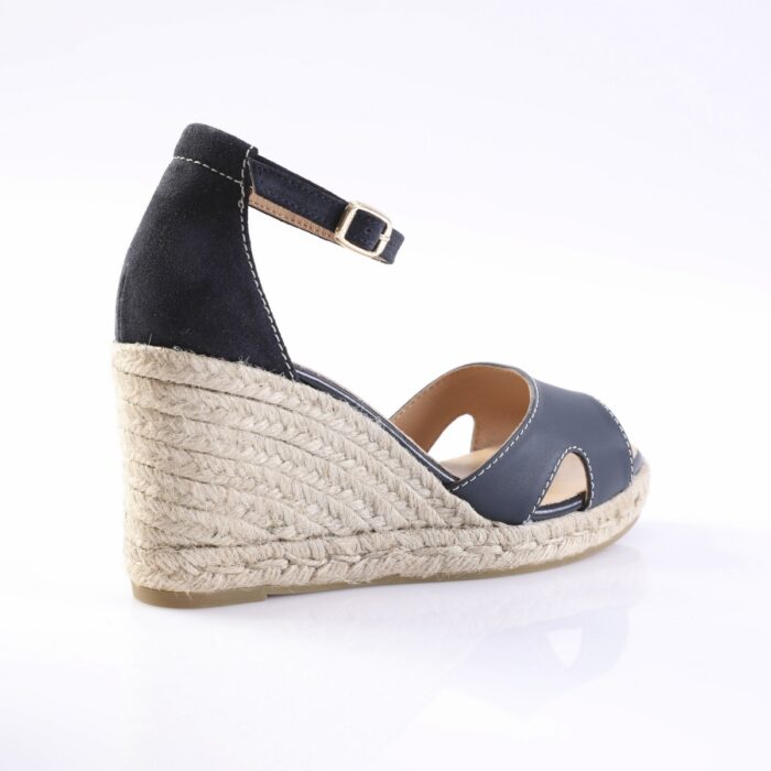 Navy wedge sandal with ankle strap, white stitching, and a braided jute midsole on a light sole.