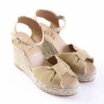 Beige fabric wedge espadrille sandals with braided jute sole, bow accents on the toe, and an ankle strap with a buckle.