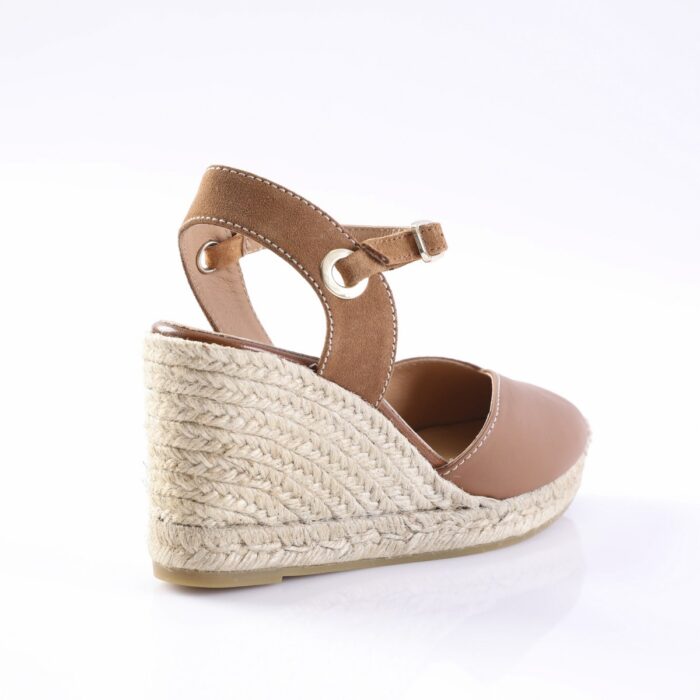 Brown leather wedge espadrille sandal with an ankle strap and buckle, viewed from the side showing the braided jute wedge heel and beige sole.