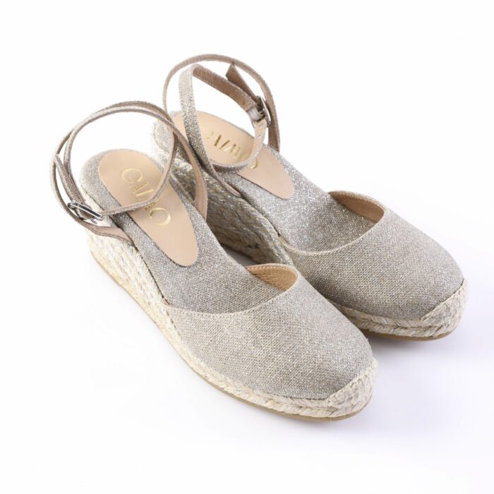 Beige glitter espadrille wedge sandals with ankle straps, shown on a white background, featuring a woven rope sole and almond toe.