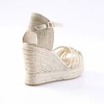 Gold wedge espadrille sandal with braided jute sole and thin ankle strap, shown from the back-left side