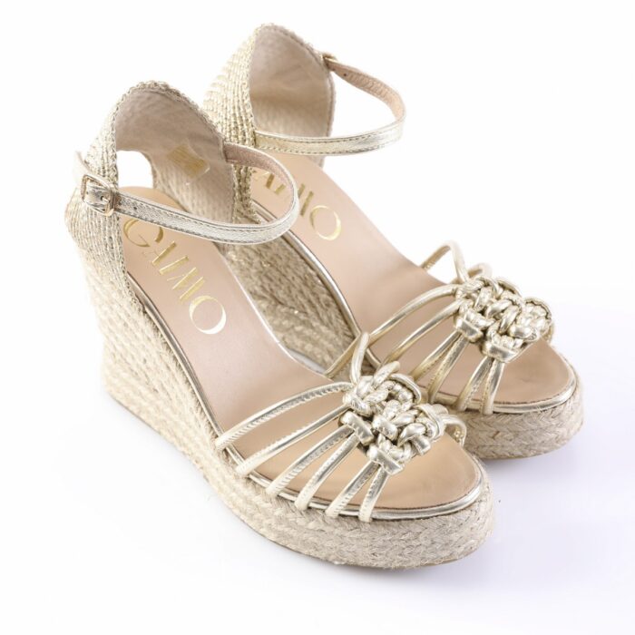 Gold metallic wedge sandals with braided front straps, open toes, and ankle buckle on a white background