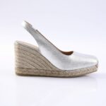 Silver metallic slingback espadrille wedge with a braided jute sole on a white background, showcasing an open toe and ankle strap.