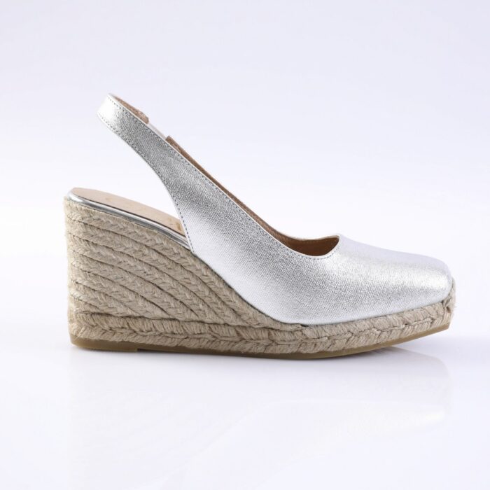 Silver metallic slingback espadrille wedge with a braided jute sole on a white background, showcasing an open toe and ankle strap.
