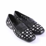 Pair of black leather loafers with silver circular studs and a strap across the vamp, on a white background.