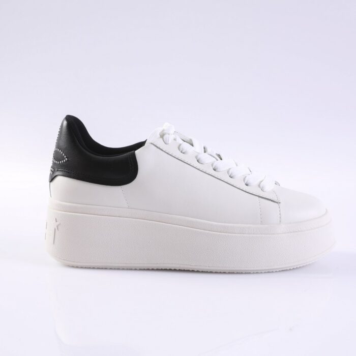 White platform sneaker with white laces and a black heel panel seen from the side. The shoe has a thick sole and subtle star detail on the heel area.