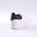 White platform sneaker with a black studded heel patch and white laces, shown in three-quarter rear view.