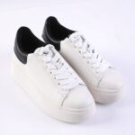 White platform sneakers with black padded heel collar and white laces on a white background.