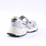 White and silver athletic sneaker with a Velcro strap and chunky, wavy midsole viewed from the rear-left side.