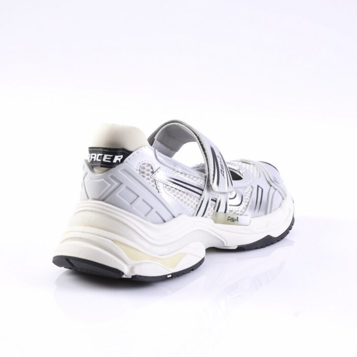 White and silver athletic sneaker with a Velcro strap and chunky, wavy midsole viewed from the rear-left side.