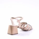 Beige strappy block-heel sandal shown from rear-right, highlighting ankle strap and gold buckle.