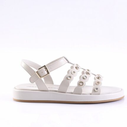 White sandal with decorative circular metal embellishments along the straps and an adjustable buckle strap, flat sole