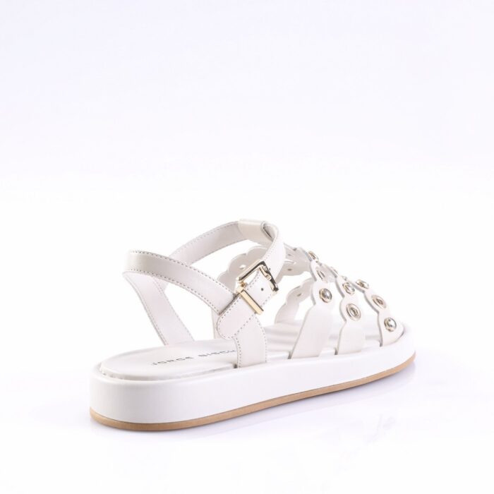 White leather sandal with multiple straps, gold buckle, and round metal grommets on a white platform sole with a light brown outsole